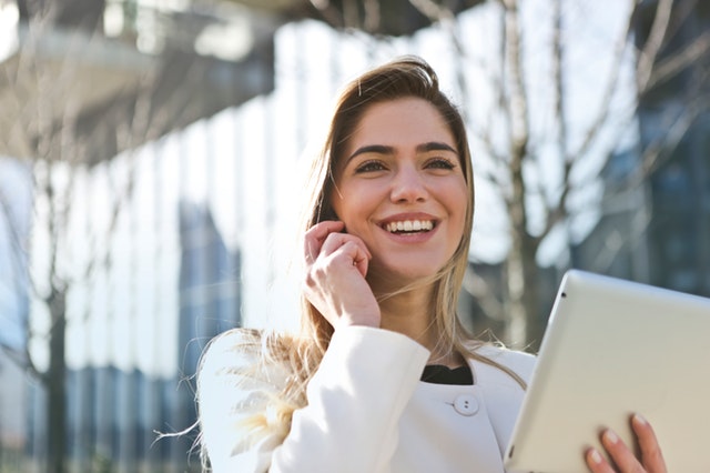 Žena sa pozerá do tabletu a telefonuje